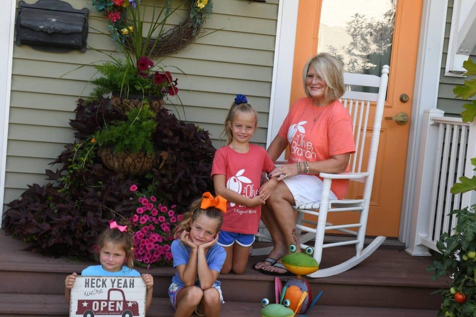 Sandi Fruitt sitting on the porch of the Olive Branch with her granddaughters