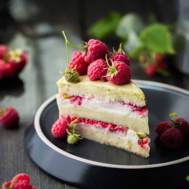 Layered cheesecake dessert topped with wild raspberries