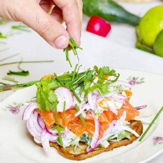 Salmon toast topped with cilantro and red onion slices