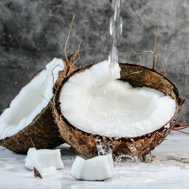 Coconut cut in half with water pouring into it