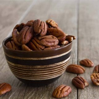 Small striped wooden bowl full of pecans