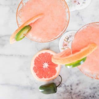 Glasses of pink grapefruit juice garnished with sliced grapefruit and jalapeno