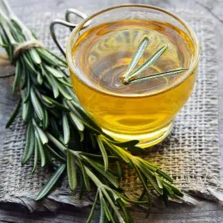 Rosemary infused extra virgin olive oil poured in a small glass cup