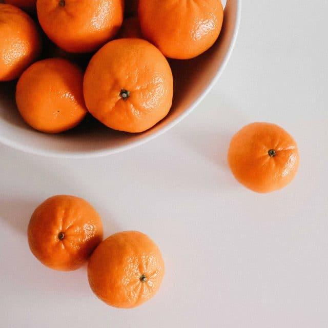 White bowl full of tangerines