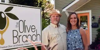 Billy and Maria Hutchison in front of The Olive Branch sign