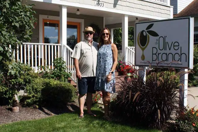 Billy and Maria Hutchison standing next to The Olive Branch exterior sign