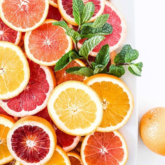 Sliced lemons, oranges, grapefruits, and blood oranges with springs of mint