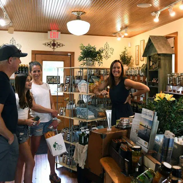 Owner Maria Hutcheson smiling at the camera while customers smile and laugh at The Olive Branch