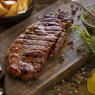 Steak marinade with olive oil and herbs on a wooden board