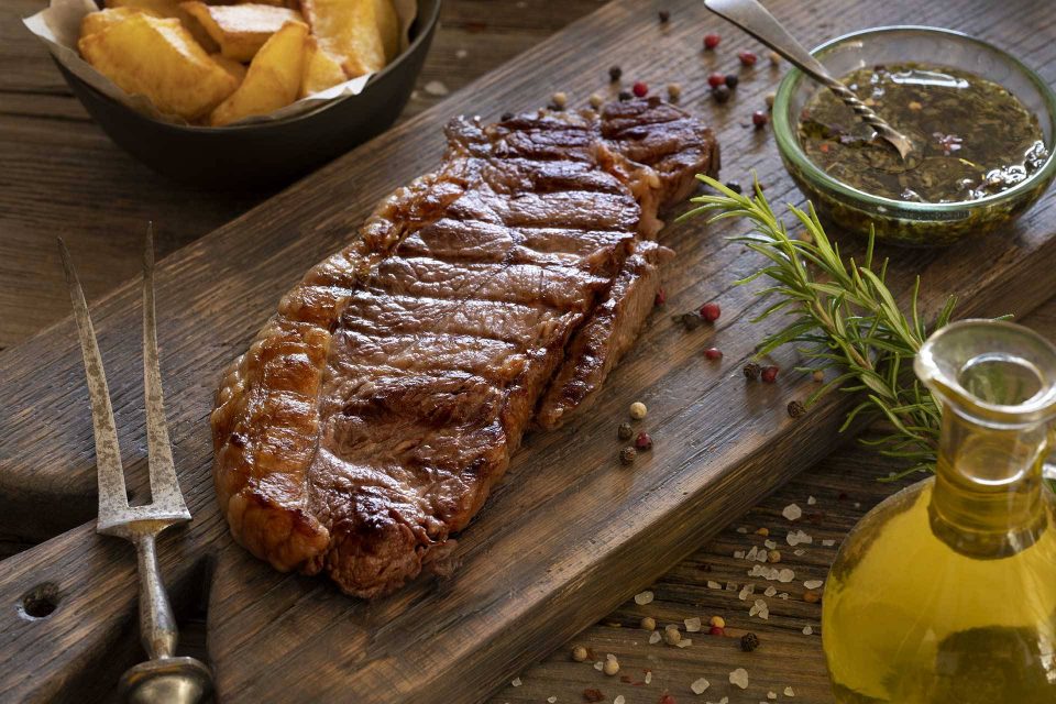 Steak marinade with olive oil and herbs on a wooden board