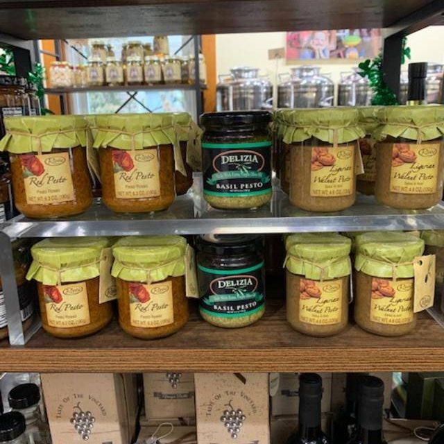 Jars of basil pesto, walnut pesto, and red pesto on a shelf at The Olive Branch