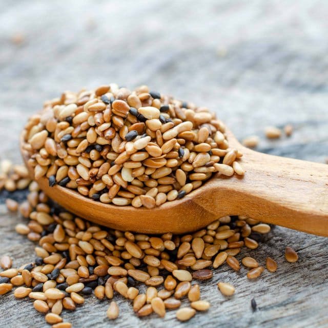 Wooden scoop full of toasted sesame seeds