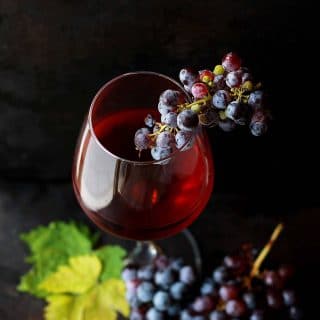 Red wine vinegar in a wine glass with red grapes as a garnish