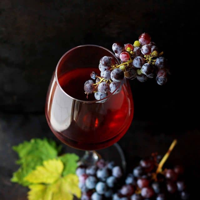 Red wine vinegar in a wine glass with red grapes as a garnish